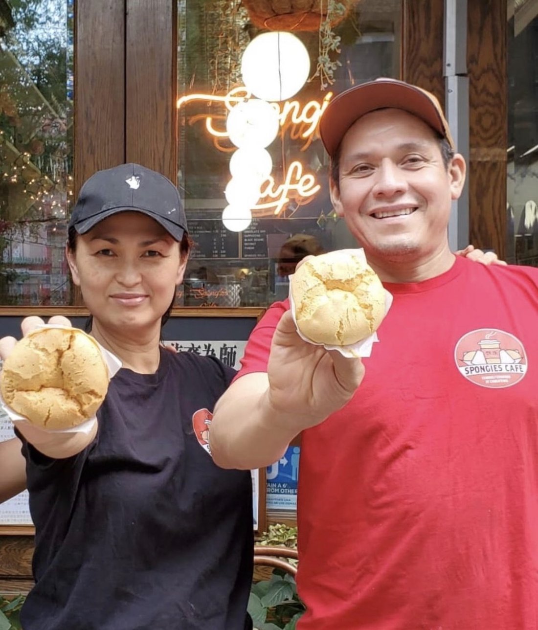 Sasinee and Fernando, the family behind the counter at Spongies Cafe, holding fresh sponge cakes